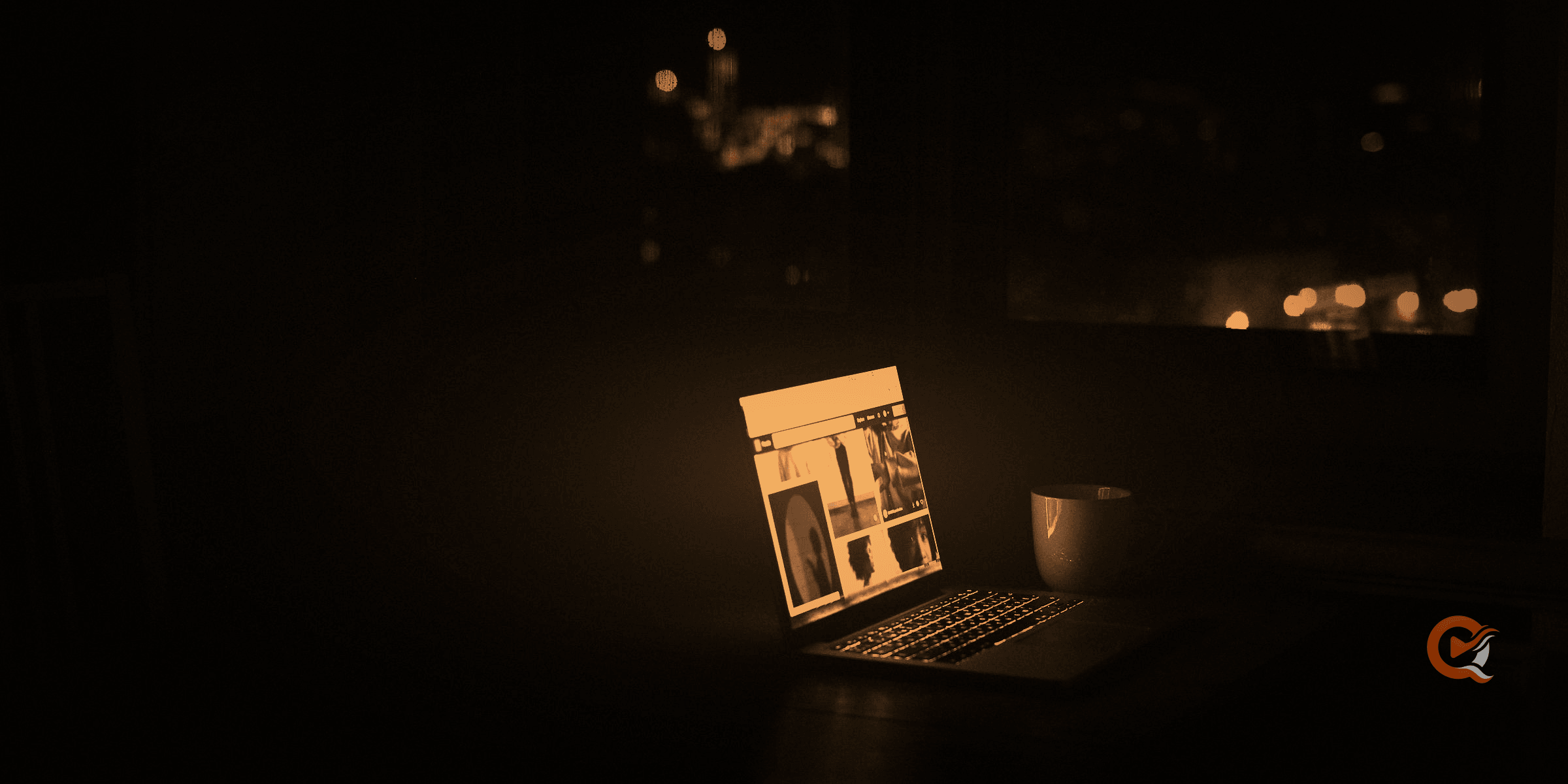 A laptop playing in a dark room at night, city lights blurred behind the window